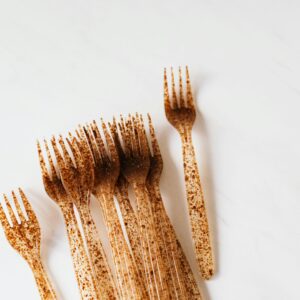 Transparent in brown spots disposable plastic forks placed in bunch on white table