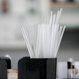 Close-up of plastic drinking straws in a black container, blurred background.